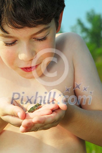 Young boy holding a tiny green frog in his hands Young boy holding a tiny green frog in his hands