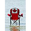 Folding chair with canadian flag design in shallow lake water