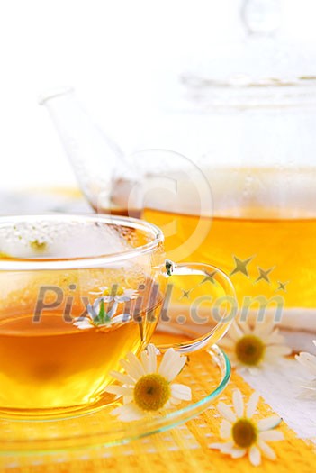 A teacup and a teapot with soothing herbal camomile tea A teacup and a teapot with soothing herbal camomile tea