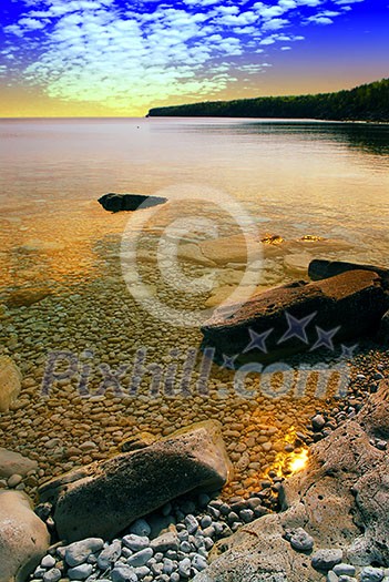 Beautiful view on a rocky shore with clear water and golden reflections at sunset. Georgian Bay, Canada. Beautiful view on a rocky shore with clear water and golden reflections at sunset. Georgian Bay, Canada.