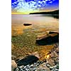 Beautiful view on a rocky shore with clear water and golden reflections at sunset. Georgian Bay, Canada.