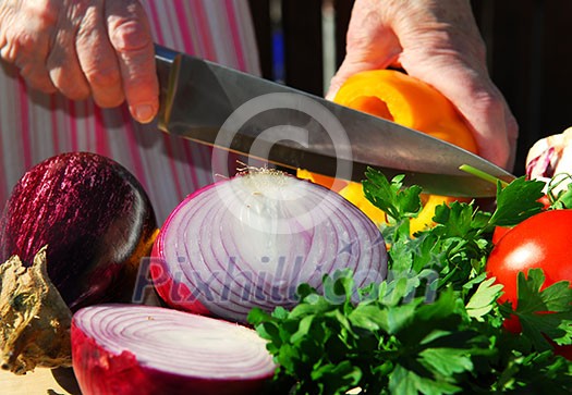 Hands of an elderly woman cutting fresh vegetables