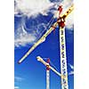 Two construction cranes on blue sky background