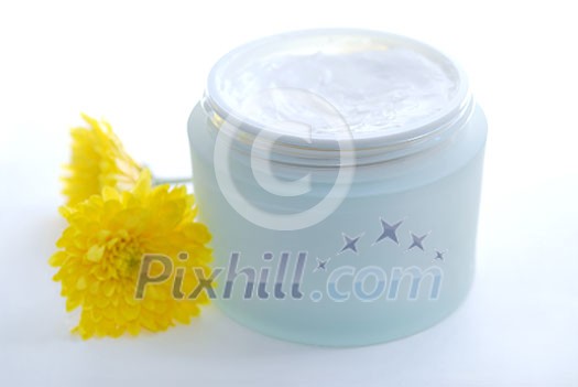 Open jar of a luxury cream with yellow flowers