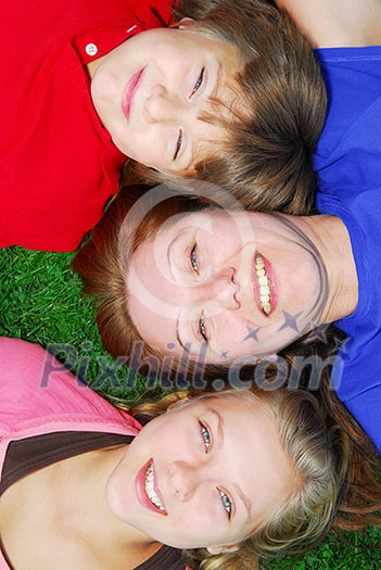 Portrait of a family - mother and children - lying on grass in a park