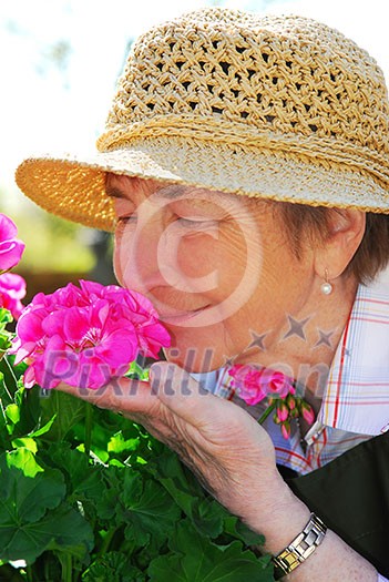 Portrait of a happy senior woman in her garden smelling flowers
