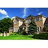 Large upscale residential home with bright green lawn and blue sky