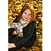 Portrait of a beautiful teenage girl in a fall park with fallen leaves