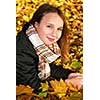 Portrait of a beautiful teenage girl in a fall park with fallen leaves