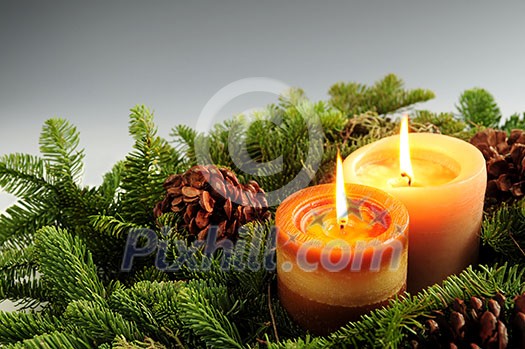 Christmas arrangement of burning candles and green spruce branches, background