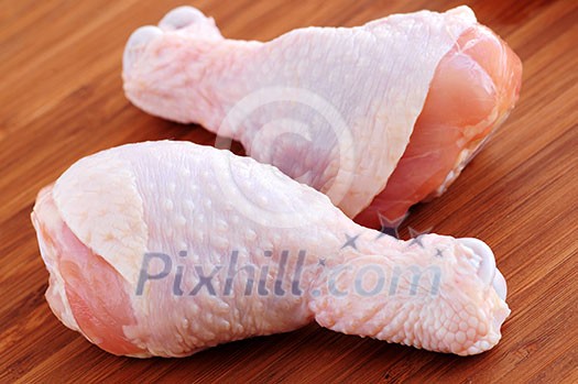 Raw chicken drumsticks on a wooden board Raw chicken drumsticks on a wooden board