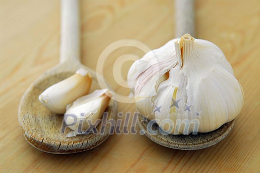 Bulbs and cloves of garlic on wooden cooking spoons Bulbs and cloves of garlic on wooden cooking spoons