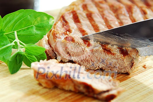 Grilled steak being cut on a cutting board, closeup Grilled steak being cut on a cutting board, closeup