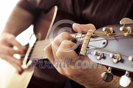 Hands of a person playing an acoustic guitar close up