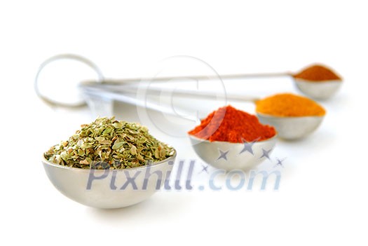 Assorted spices in metal measuring spoons on white background Assorted spices in metal measuring spoons on white background