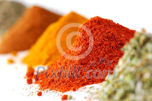 Heaps of various ground spices on white background