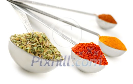 Assorted spices in metal measuring spoons on white background Assorted spices in metal measuring spoons on white background
