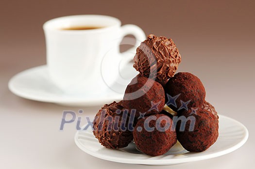 Gourmet chocolate truffles on a plate with a cup of coffee
