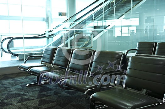 Row of chairs and escalator inside an airport