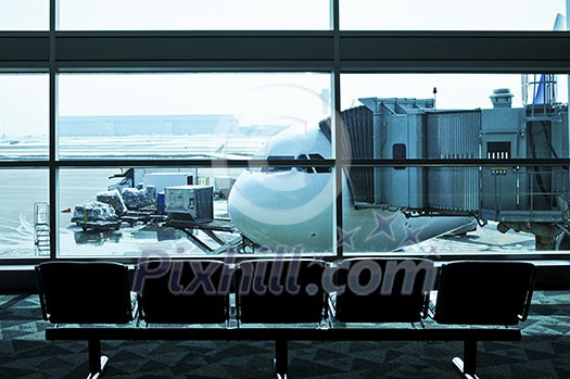Waiting area of airport gate with airplane outside