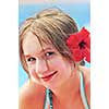 Portrait of a young girl on tropical beach with red flower