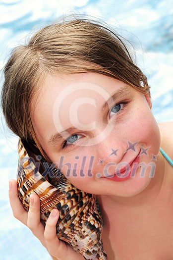 Happy young girl holding a large seashell on tropical beach Happy young girl holding a large seashell on tropical beach