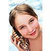 Happy young girl holding a large seashell on tropical beach