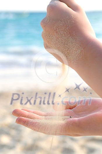 Hands pouring fine sand on a beach