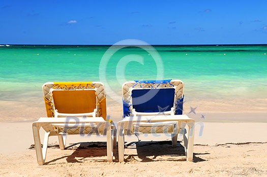 Two vacation chairs on sandy beach of Caribbean island