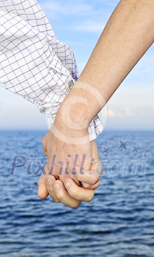 Mature romantic couple holding hands on the beach Mature romantic couple holding hands on the beach