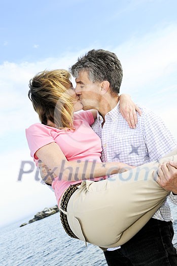 Mature romantic couple of baby boomers kissing on a beach