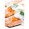 Cooked salmon fillets with dill sauce on white plate