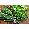 Bunches of assorted fresh herbs close up on wooden cutting board