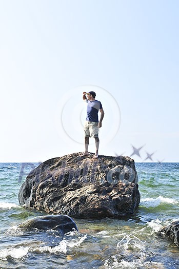 Man stranded on a rock in ocean waiting for rescue Man stranded on a rock in ocean waiting for rescue