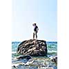 Man stranded on a rock in ocean waiting for rescue