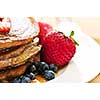 Stack of buckwheat pancakes with fresh berries and maple syrup