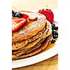 Stack of buckwheat pancakes with fresh berries and maple syrup