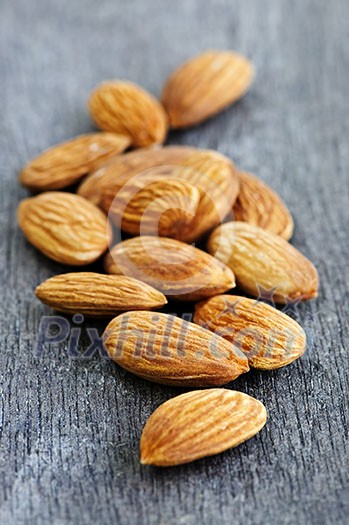 Raw almonds in a pile on wooden surface Raw almonds in a pile on wooden surface