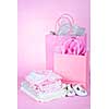 Gift bags and infant clothes for girl baby shower on pink background