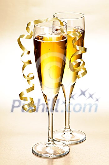 Two full champagne flutes with sparkling wine and ribbon