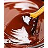 Wooden spoon stirring soft melted rich chocolate