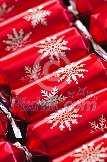 Closeup of many red Christmas crackers in a row