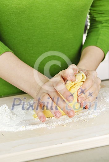 Hands kneading ball of dough with flour on cutting board