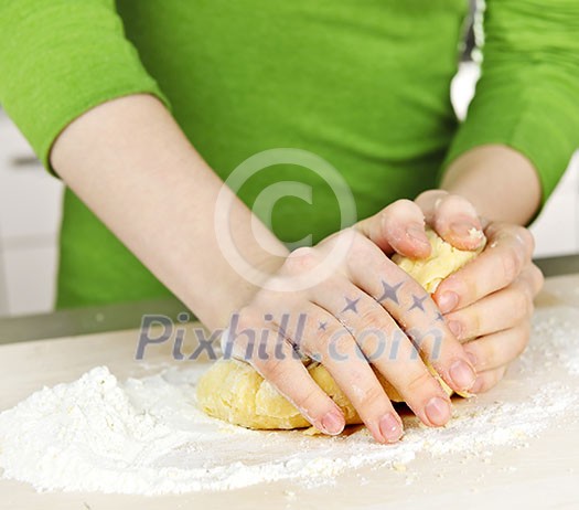 Hands kneading ball of dough with flour on cutting board Hands kneading ball of dough with flour on cutting board
