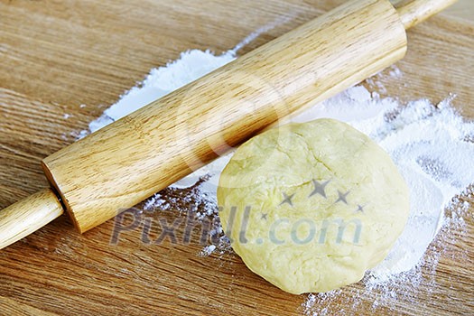 Wooden rolling pin and ball of cookie dough with flour Wooden rolling pin and ball of cookie dough with flour