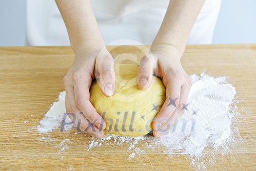 Hands kneading ball of dough with flour on cutting board Hands kneading ball of dough with flour on cutting board