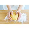 Hands kneading ball of dough with flour on cutting board