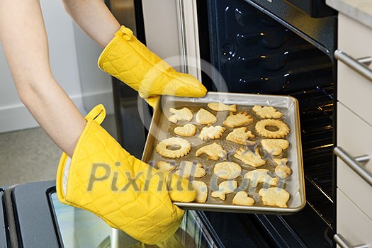 Taking fresh baked shortbread cookies from oven in kitchen Taking fresh baked shortbread cookies from oven in kitchen