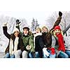 Group of excited young friends with arms raised outdoors in winter