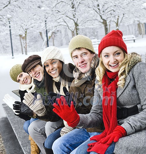 Group of diverse young friends waving hello outdoors in winter